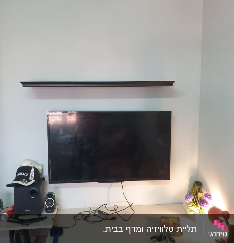 מדף תלוי מעל טלוויזיה עם חוטים על שולחן